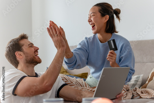 Bild auf Leinwand Happy multicultural couple celebrating online purchase, high-fiving while using
