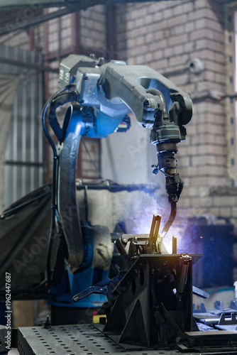 Foto Industrial robot performing arc welding on metal detail in factory