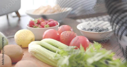 Perforated mesh sweeping frame, revealing strawberries, kiwis, striped arm passing behind for food