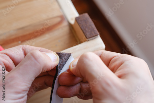 Fotografie Hands applying adhesive felt furniture pads protecting wooden floor