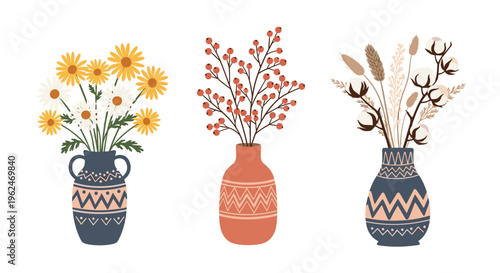 Set of three decorative ceramic vases containing arrangements of yellow daisies, red berries, and white cotton plant stalks on white.