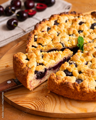 Foto Delicious homemade cherry crumble pie with fresh mint garnish on a wooden board