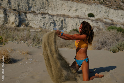 Happy woman playing with sand on a sunny beach vacation	
