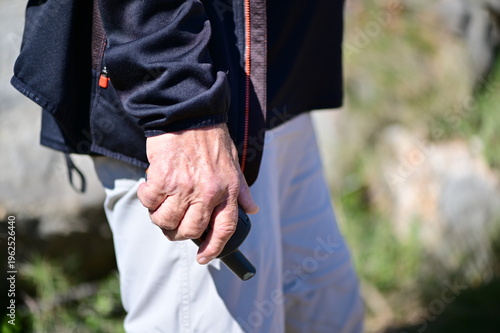 An elder man holds a navigation system for walking in the mountains.