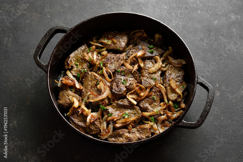 Bild auf Leinwand Sauteed liver with butter and onion in pan on black stone background