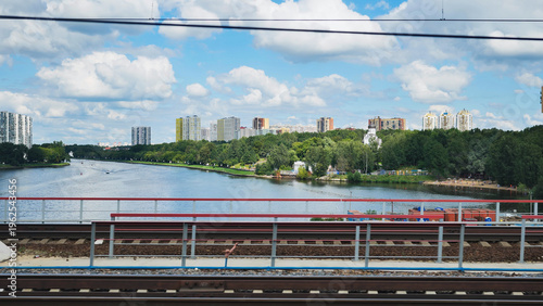 Photography Urban skyline with river, green trees, apartment buildings, and a bridge
