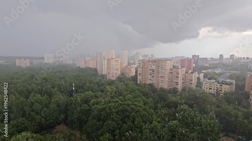 City skyline with a large rain cloud in the sky. The city is surrounded by trees and buildings