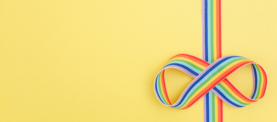 Autism acceptance month, Autism awareness day concept. Rainbow ribbon in shape of infinity on yellow background