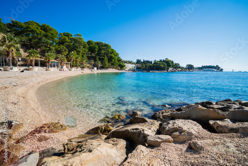 a beautiful beach with a view of the Adriatic Sea with rocks on the shore and pine trees in Split, Croatia