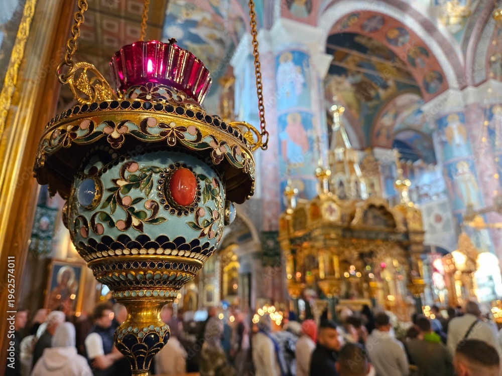 Fototapeta premium Large crowd of people are gathered in a church, with a large gold and blue candle holder hanging from the ceiling. The candle holder is lit, and the people are standing around it