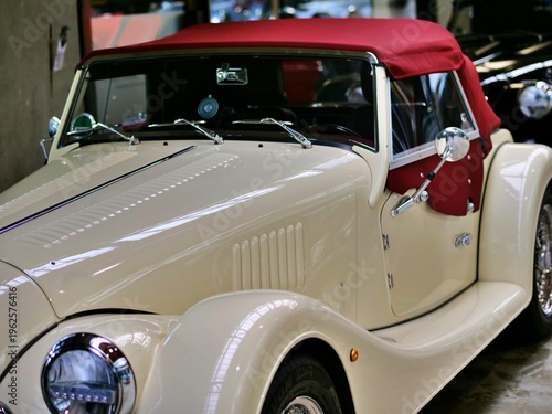 Foto Close-up of a classic cream-colored Morgan Plus 4 convertible with a
vibrant red soft top