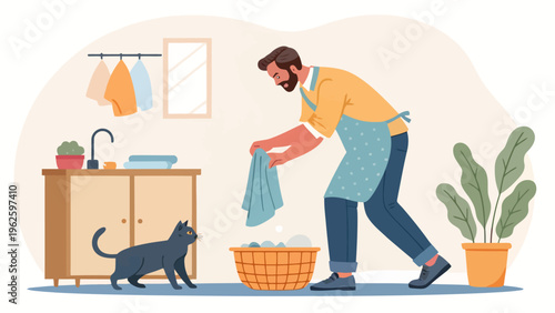 A man in a yellow shirt and blue apron is doing laundry with a black cat nearby in a clean and cozy kitchen