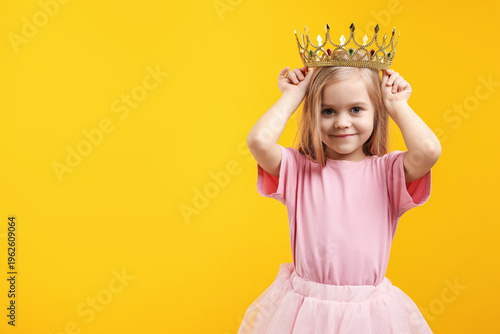 Bild auf Leinwand Beautiful little girl with crown dreaming about becoming queen on orange backgro