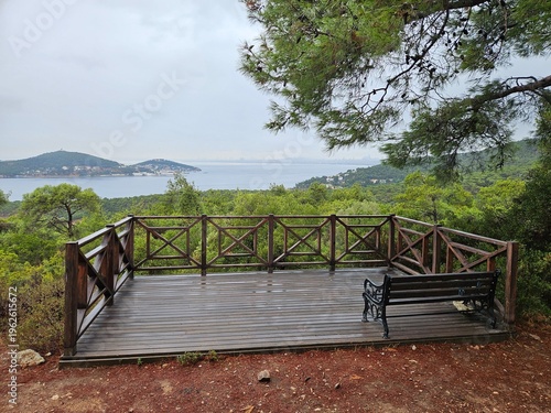 Wallpaper Mural Wooden deck overlooking a body of water with a bench and railing. The bench is empty. The deck is surrounded by trees and the view is serene and peaceful Torontodigital.ca