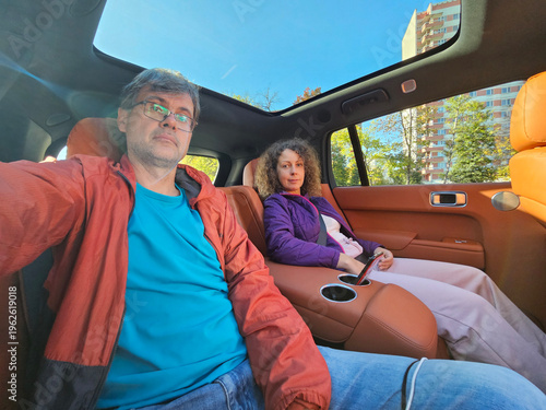 Wallpaper Mural Man and woman are sitting in a car with a woman holding a cell phone. The man is wearing a blue shirt and the woman is wearing a purple jacket Torontodigital.ca