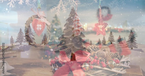 Digital video depicts a snowy scene with fir trees and a decorated wreath.