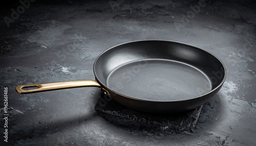 Nonstick frying pan on dark textured surface for gourmet cooking and culinary arts. Professional kitchenware for chef prepared meals.