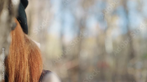 Caucasian woman masked prowler in woods, sunglasses and knit scarf conceal face, red hair peeking from beanie, closeup portrait with soft autumn bokeh, tense stealthy mood suggesting snatcher