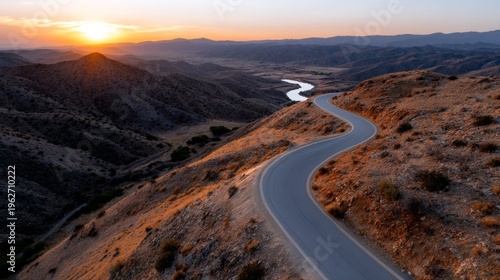 The sun rises over a winding road through arid valleys in California..