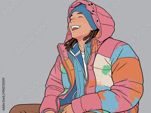 Young person wearing colorful jacket and hat while laughing indoors with a gray background