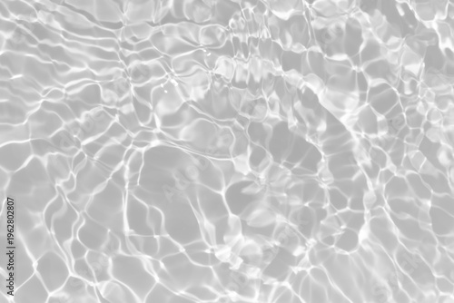 White water with ripples on the surface. Defocus blurred transparent white colored clear calm water surface texture with splashes and bubbles. Water waves with shining pattern texture background.