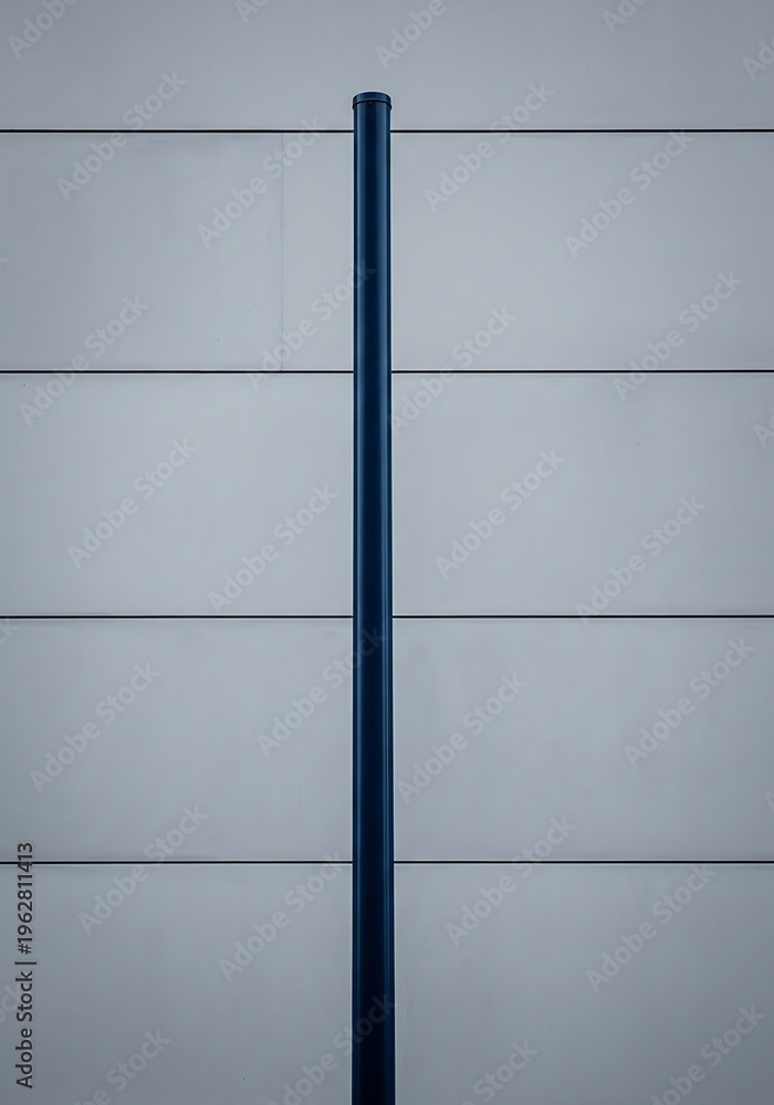 Fototapeta premium Vertical Steel Pipe Against Horizontal Panelled Building Facade Simplicity