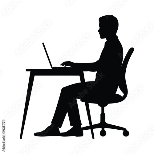 A silhouette of a man sitting at a desk working on a laptop