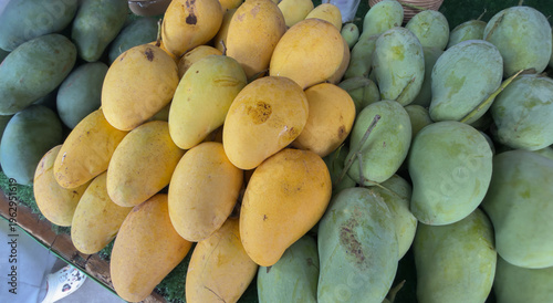 Foto Combination of green and ripe mangoes displayed together at a market stall