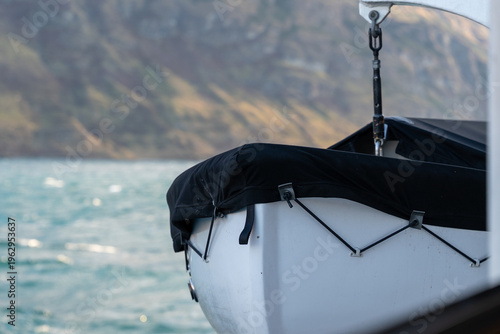 Foto White dinghy boat bow black cover crane sea  misty mountains