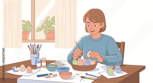 A woman sits at a wooden table, painting colorful eggs with various art supplies scattered around her in a room with a window.