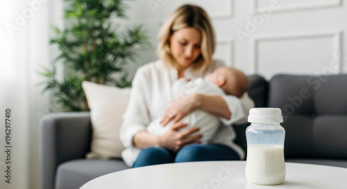 A woman sitting on a couch with a baby and a bottle of milk