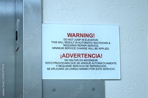 Close-up of a warning sign inside an elevator stating not to jump, written in English and Spanish. Concept of safety rules, public instructions, and building regulations.
