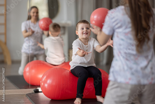 Child Physical Therapy Session With Therapist Using Red Exercise Ball In Pediatric Rehab Clinic