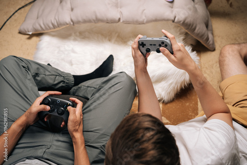 Obraz na płótnie Close-up of two male friends gaming together at home, enjoying console video games during leisure time, having fun and unwinding while sharing entertaining moments and screen time