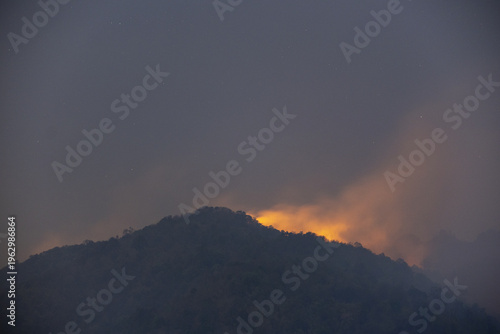 Картината върху платно Ominous wildfire smoke fills dark sky above rugged mountain peak