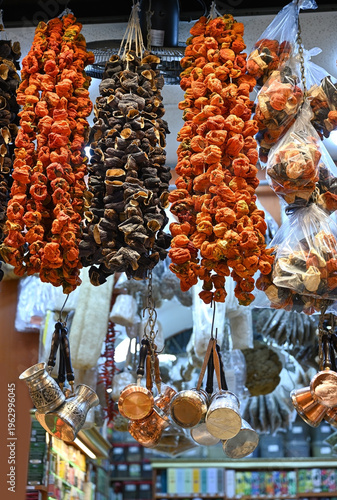 Dried peppers and eggplants hang and copper and silver Turkish coffee pots at a market stall.