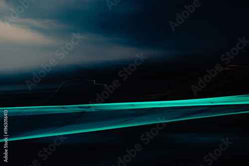 Abstract teal light streak with motion blur on dark