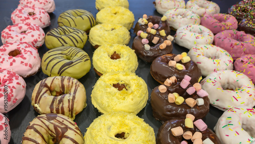 Fotografi Close-up of colorful donuts with glaze and sprinkles on display