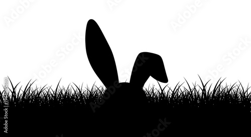 Silhouette of a rabbits ears peeking out from tall grass.