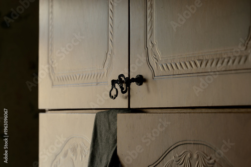 A close-up shot of a vintage white painted wooden cabinet featuring decorative carved panels