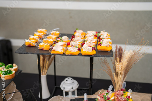Elegant arrangement of gourmet canapes and appetizers served on black slate platters at a catered event decorated
