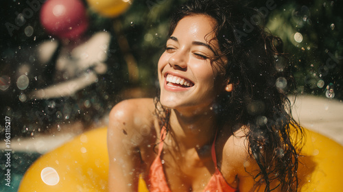 A person in a coral bikini laughing while leaning on a yellow pool float in sparkling water during a summer party.