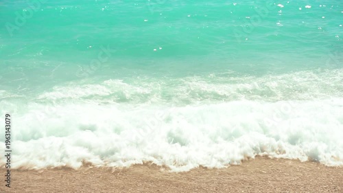 Sea surf. Sunny day on the tropical coast. Waves roll onto the sandy shore. Slow motion. Perfect for travel blogs and travel content.