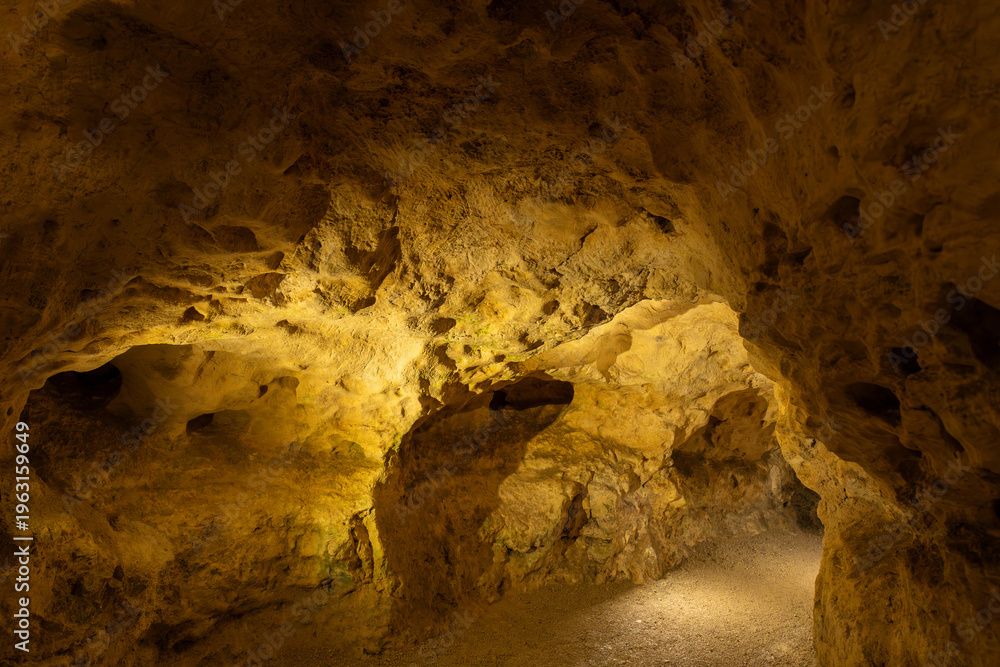 Obraz premium illuminated cave interior with rock formations and tunnel
