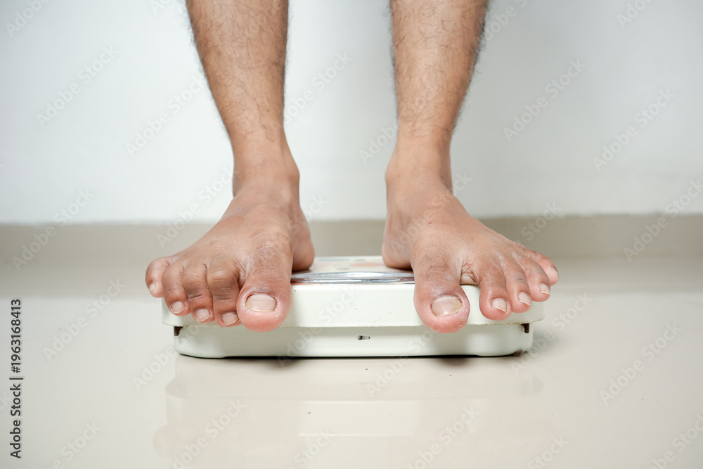 Fototapeta premium Man's Feet Standing on Weighing Scale