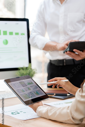 Bild auf Leinwand Business professionals analyzing sustainable energy data and ESG financial reports using tablet and calculator in office