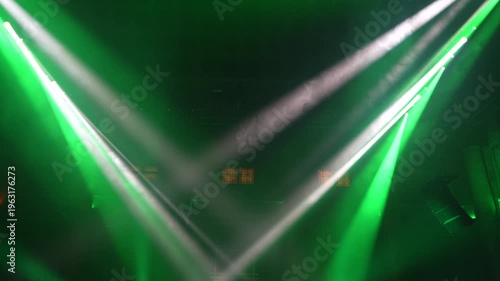 Bright green spotlights cut through the dark atmosphere of an empty stage or venue. The dynamic beams create circular patterns on the floor, evoking an energetic mood for a concert or live event.

