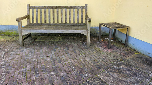 Foto Weathered wooden bench and small metal table sitting on an old brick patio
