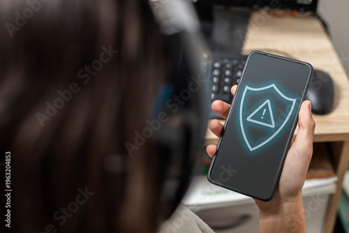 Teen hand holding smartphone showing cybersecurity alert