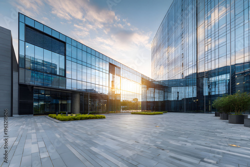 Modern office building with a glass curtain wall exterior and paved plaza area.